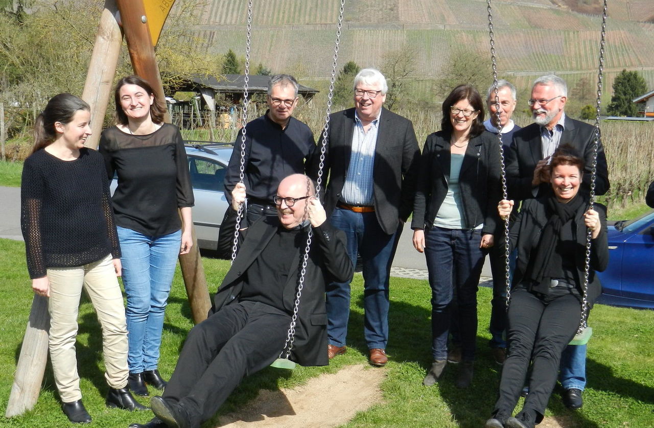 Präsident Gerold Reker und Geschäftsführerin Dr. Elena Wiezorek auf einer Schaukel, herum gruppieren sich die Vorstandsmitglieder vor einer Weinlandschaft