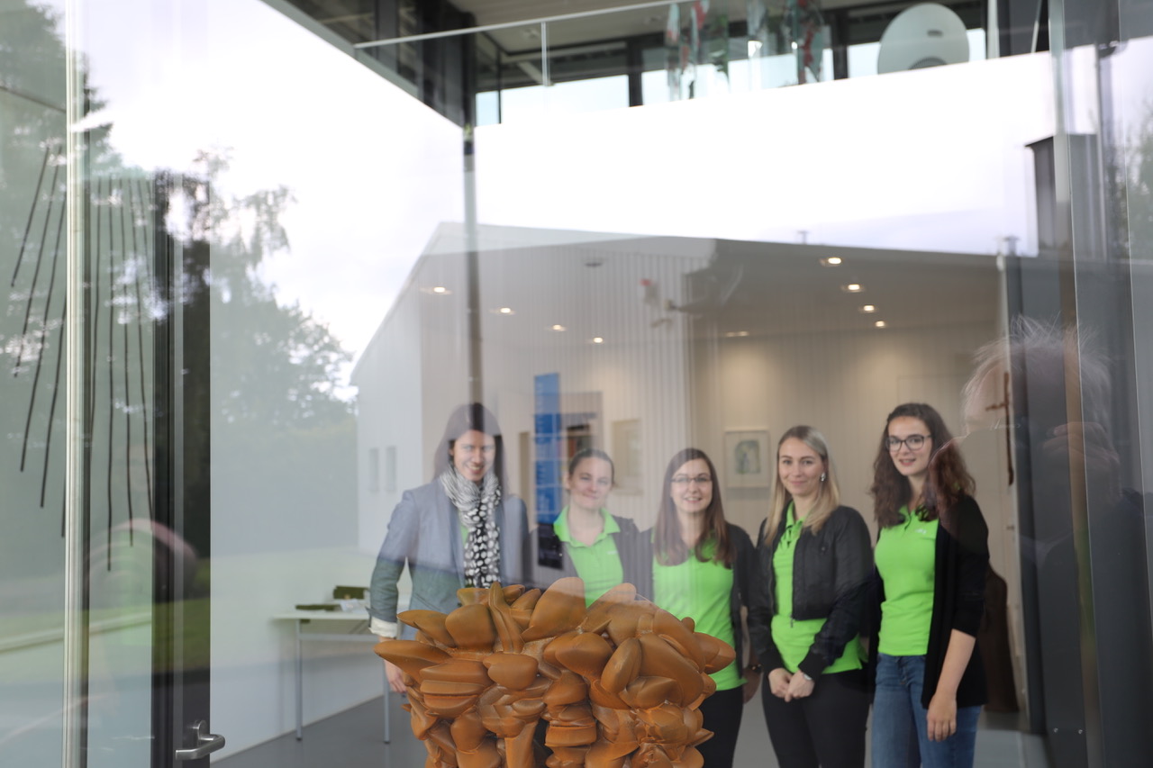 Blick durch eine Glasscheibe, hinter der eine Gruppe von fünf Frauen steht.