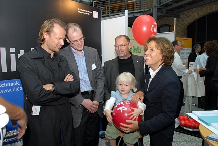 Foto: Die Umweltministerin Conrad steht im Foyer der Handwerkskammer in Mainz mit Architekten zusammen, mit dabei auch ein Kind mit rotem Unser Ener - Werbeluftballon