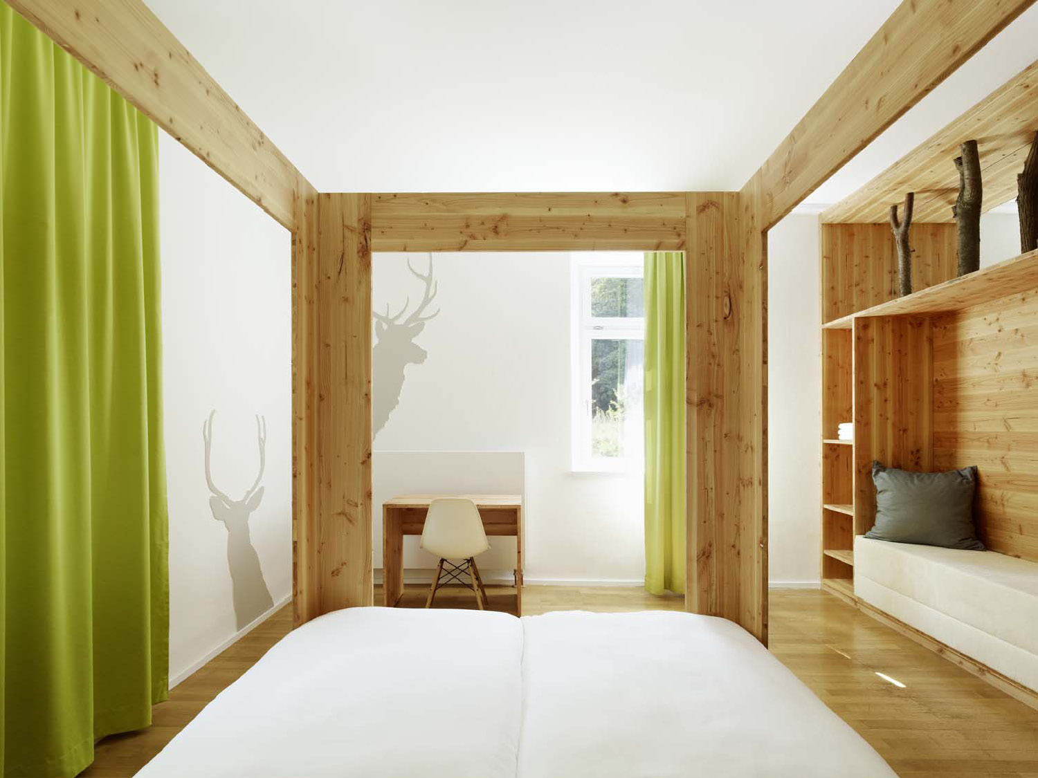 Zimmer mit Bett und Hirschgeweih und grüner Gardine