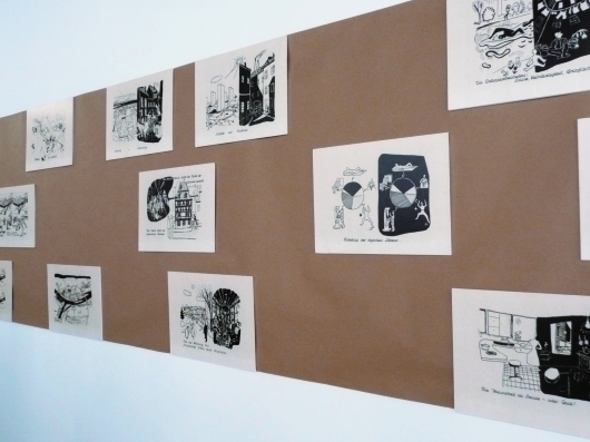 Foto: Die Federzeichnungen von Marcel Lodz hängen auf einem Packpapierband montiert an der Wand.